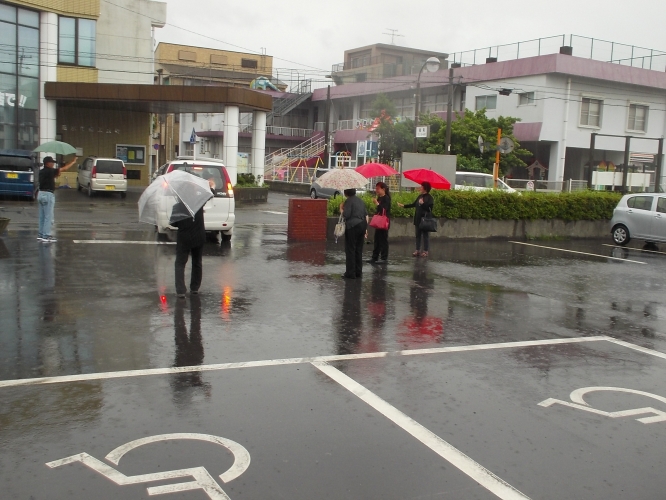 大雨の中、いつまでも見送る受け入れ家庭